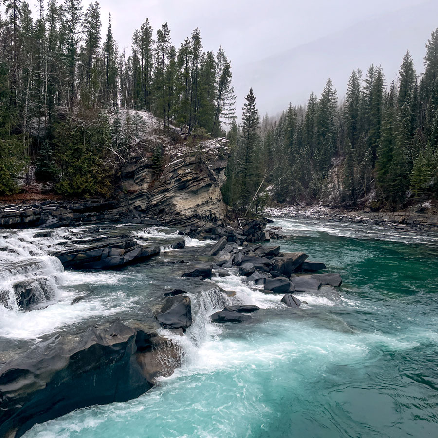 The glacial blue water for the Fraser River flowing over Rearguard Falls in the Headwaters region.