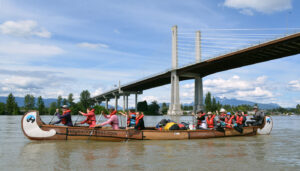Young environmental leaders paddling a Voyageur canoe under the Golden Ears bridge on the Lower Fraser River.
